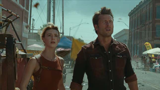 Kate and Tyler look into the distance, wind whipping their hair.